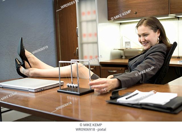 Profile of a businesswoman resting her legs on the table and smiling