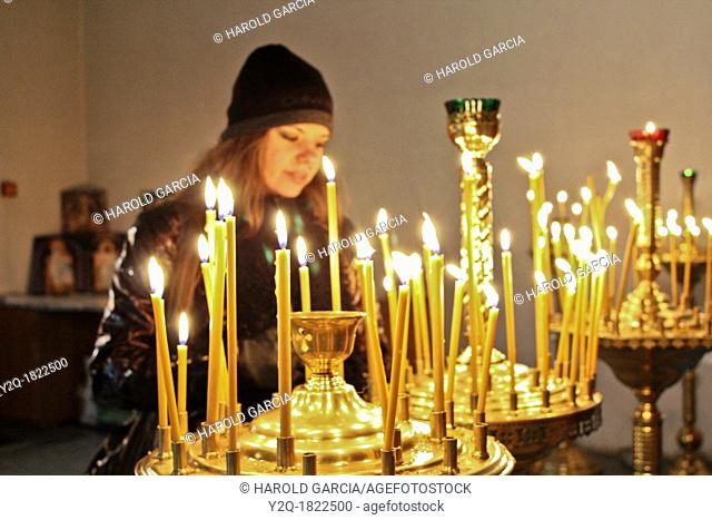 Woman lighting candles at Pechersk Lavra territory, Kiev, Ukraine