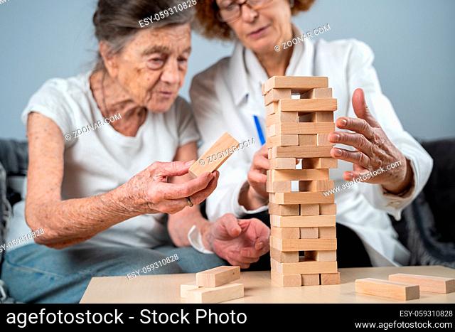 Mature doctor conducting session, therapy for senior patient in nursing home, training fine motor skills for dementia, alzheimer disease and recovery institute...
