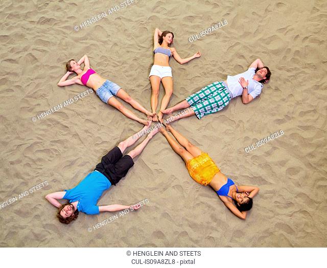Aerial view of friends lying in star shape on sand