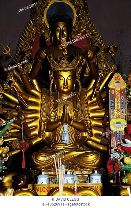Front view of seated golden statue of Avalokitesvara Bodhisattva with many arms, also known as Kuan Im godess of Loving Kindness at the Vihara Avalokitesvara...