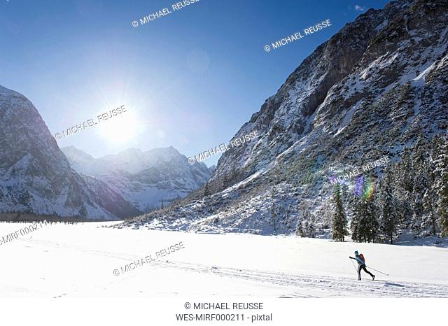 Germany, Bavaria, Senior woman doing cross-country skiing with karwendal mountains