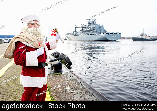 15 December 2023, Lower Saxony, Wilhelmshaven: A marine dressed as Santa Claus waves to the crew as the task force supply ship ""Frankfurt am Main"" enters the...