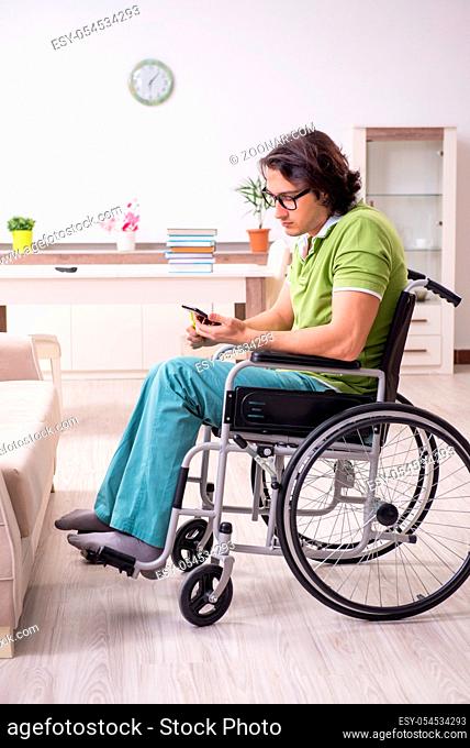 The young male student in wheelchair at home