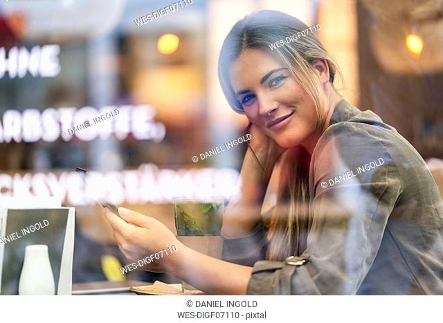 Young businesswoman in a cafe, seen through window