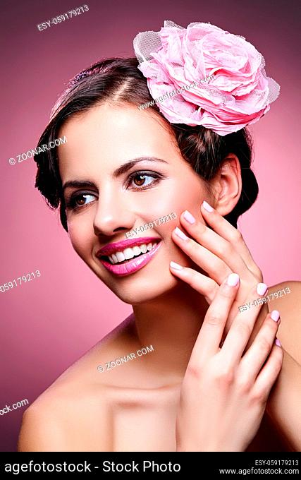 beautiful brunette happy young woman with pink lips and rose in hair. studio beauty shot. copy space