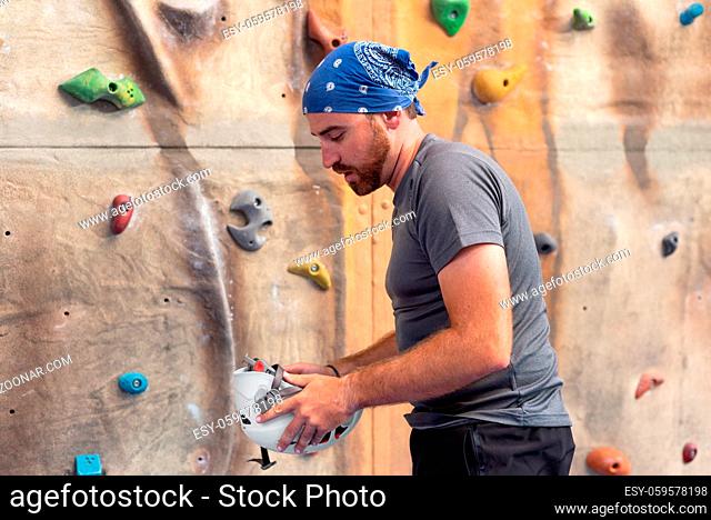 Sporty man practicing indoor rock climbing in climbing gym