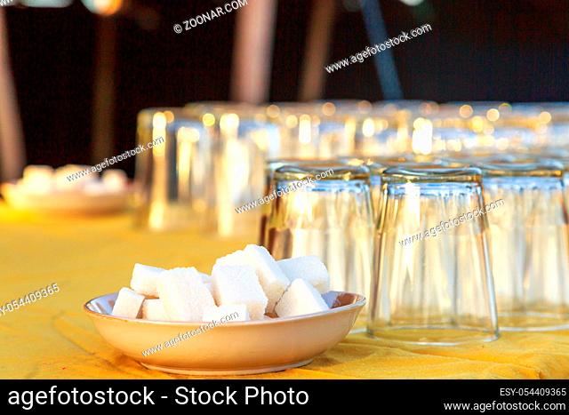 closeup on Two plates containing sugar cubes and several upside down glasses on a table