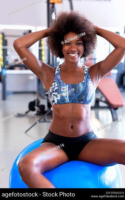 Smiling African American woman with a frizzy afro hairstyle doing pilates in the gym