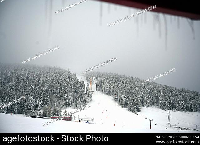 06 December 2023, Saxony, Oberwiesenthal: Icicles hang against the backdrop of the Fichtelberg. Saxony's largest alpine ski area started the season on the same...