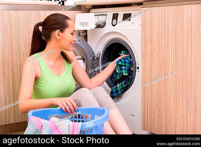 Young wife woman washing clothes near machine