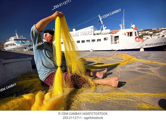 Elderly greek fisherman repairing fishnets at the old harbour, Mykonos, Cyclades Islands, Greek Islands, Greece, Europe