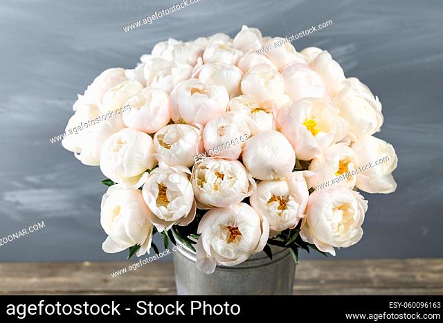White peonies in vase on wooden floor and bokeh background - retro styled photo. soft focus. close-up