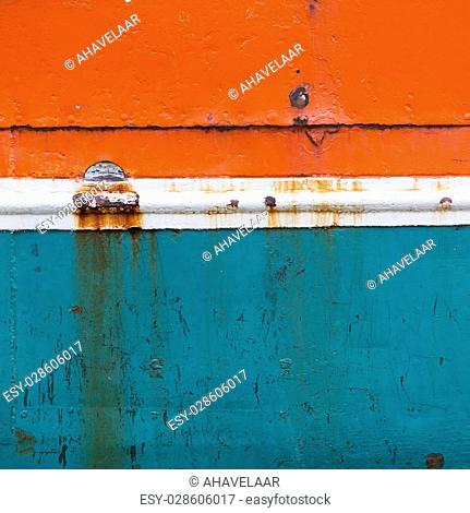 rusty metal bow of old fisher boat hull in orange blue and white