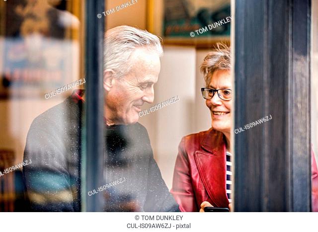Senior couple sitting at cafe window seat chatting