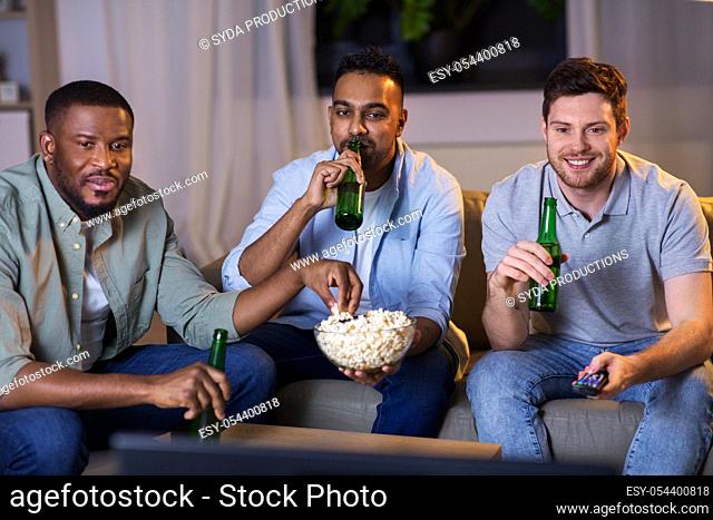 happy male friends with beer watching tv at home