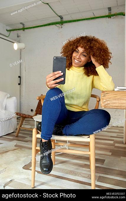 Businesswoman doing video call through mobile phone at home