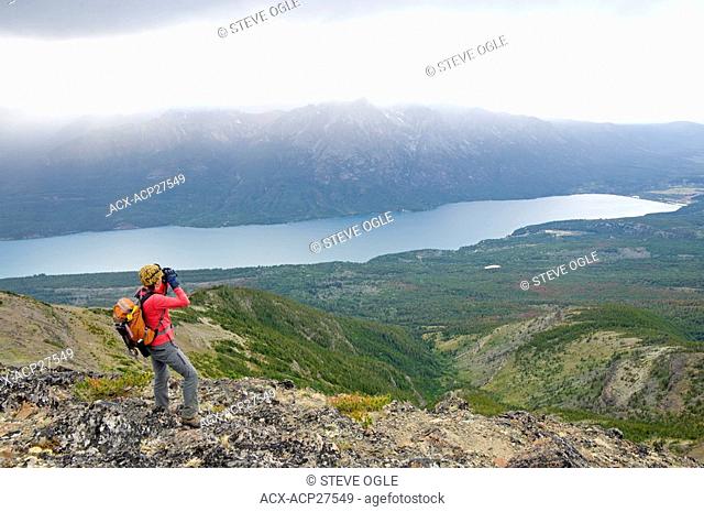A woman surveys over Tatlayoko Lake with binoculars, British Columbia Coast Mountains