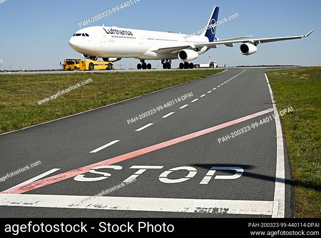 23 March 2020, Hessen, Frankfurt/Main: The word ""Stop"" is written on a street in front of the tarmac on the northwest runway at Frankfurt Airport