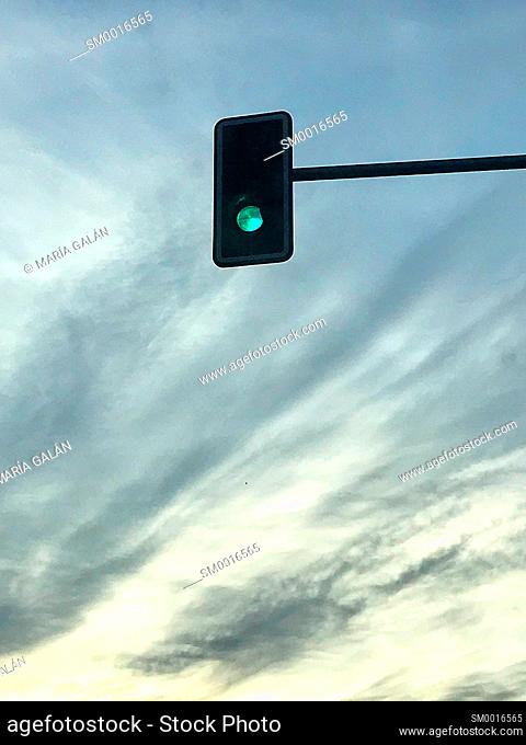 Green traffic light against nightfall sky