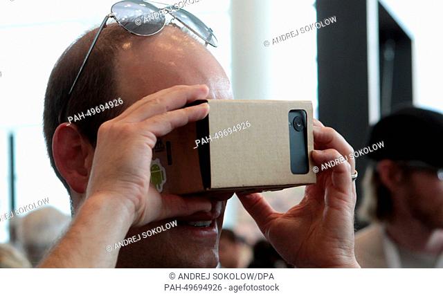 A participant examines the so-called 'Project Cardboard' which converts an android smartphone into a stereoscope with a cardboard construction during the...