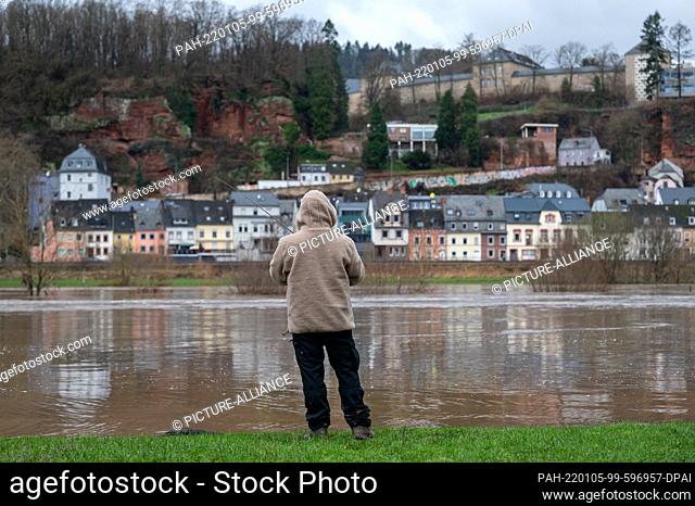 05 January 2022, Rhineland-Palatinate, Trier: A man fishes on the flooded Moselle. Several roads along the river are closed due to flooded lanes