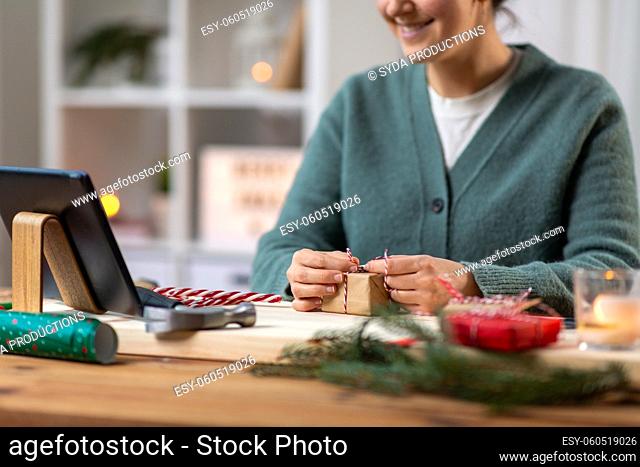 happy woman with tablet pc packing christmas gift