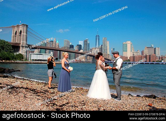 PRODUCTION - 02 August 2022, US, New York: The bride and groom Annika Heisig (m) and Patrick Brosch (r) stand at their wedding ceremony with the registrar
