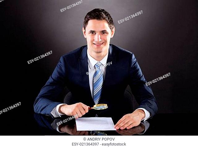 Businessman Examining Contract Paper With Magnifying Glass
