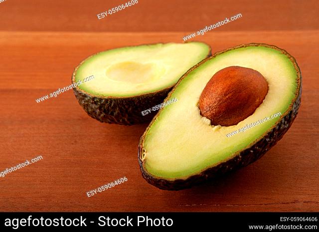 Avocado cut in half on wooden board background. Ingredient for vegetarian dishes, healthy eating