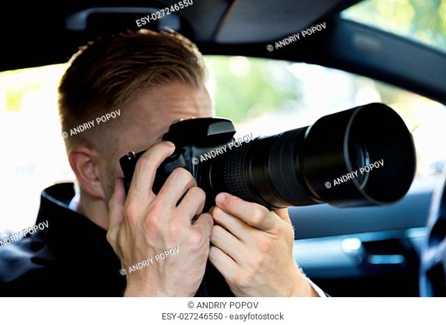 Private Detective Sitting Inside Car Photographing With SLR Camera