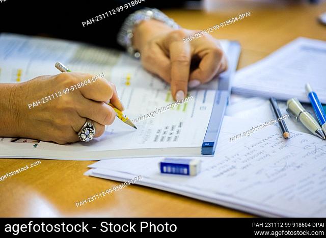 09 November 2023, Berlin: A participant in a German course at a Berlin language school writes in a learning book. Photo: Christoph Soeder/dpa