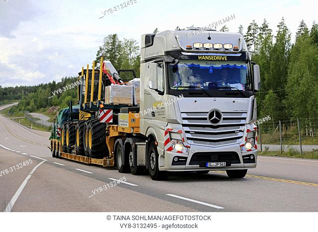 ORIVESI, FINLAND - AUGUST 27, 2018: Mercedes-Benz Actros semi trailer of Hansedrive transports forest machinery on highway in Finland on overcast day