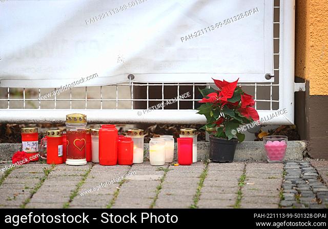13 November 2022, Bavaria, Weilheim: Candles and flowers stand in front of a house. In Weilheim, a bloody crime has occurred with four dead
