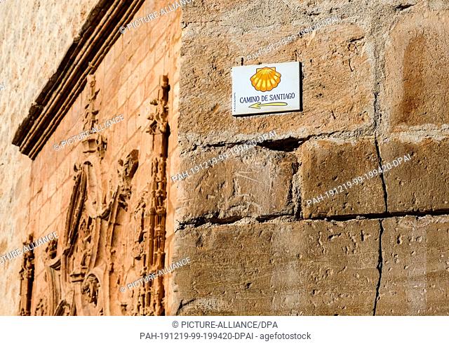24 September 2019, Spain, Tembleque: A sign on the wall of a church indicates the Camino de Santiago on the Ruta de Don Quijote