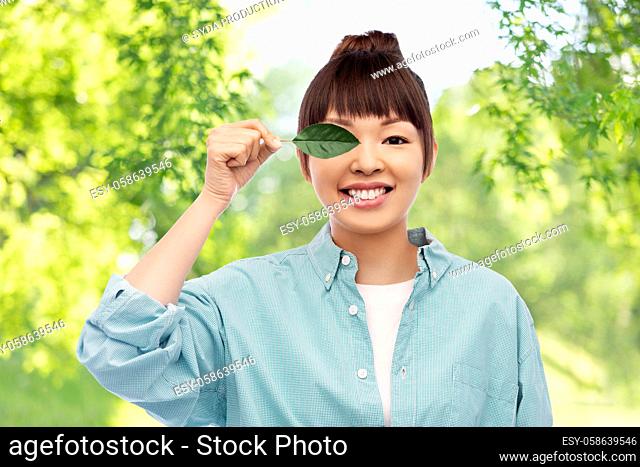 smiling asian woman holding green leaf