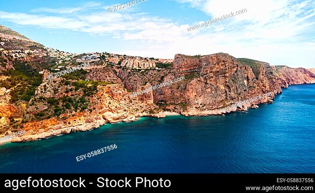 Aerial photo drone point of view picturesque Cala del Moraig in Benitachell coastal town. Bright turquoise waters bay of Mediterranean Sea white sandy beach