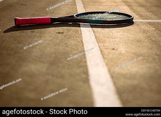 Surface level of tennis racket on white lines at tennis court during sunset, copy space