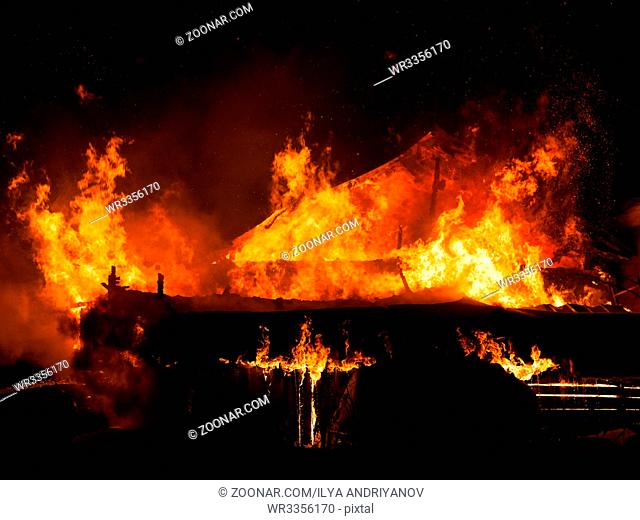 Arson or nature disaster - burning fire flame on wooden house roof