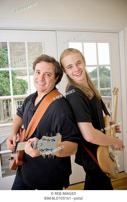 Caucasian father and son playing guitars