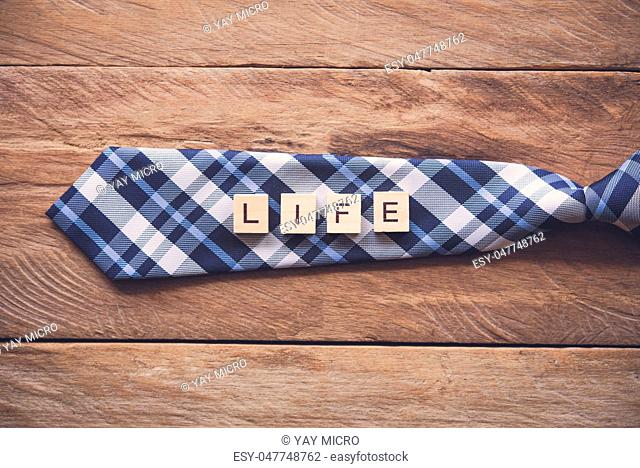 Necktie and the message ""Live"" put on wooden floor - Concept of life