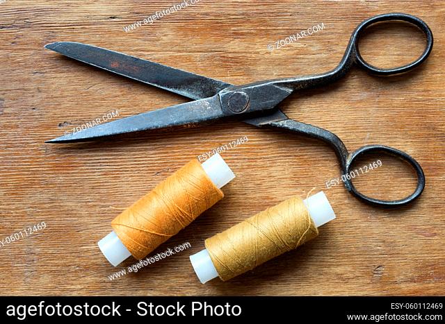 vintage scissors on the red wooden background with two spools of threads