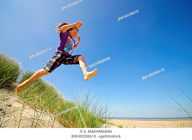 energetic boy jumping out of the dunes, Netherlands