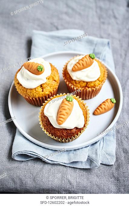 Carrot muffins topped with cream cheese frosting and marzipan carrots