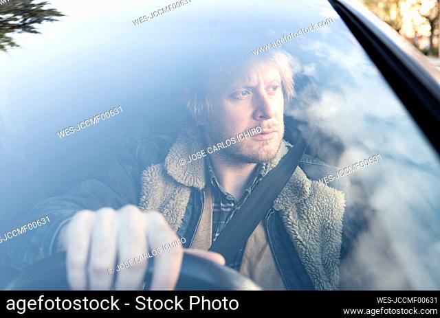 Close-up of thoughtful man sitting in car seen through windshield