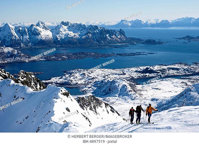 Ski mountaineers ascending to Rundfjellet, behind the Norwegian Sea, Svolvaer, Austvågøy, Lofoten, Norway