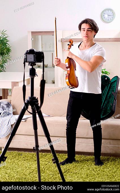 Young male blogger playing violin at home