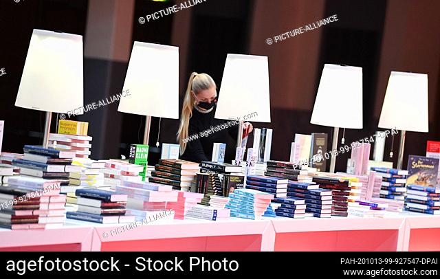 13 October 2020, Hessen, Frankfurt/Main: A Frankfurt Book Fair employee is standing at a bookstall in the Festhalle before the Frankfurt Book Fair's opening...