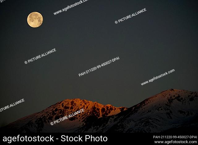 dpatop - 20 December 2021, Italy, Brixen: The moon stands in the morning hours above the village of Brixen in South Tyrol near the Liffelspitze in the east