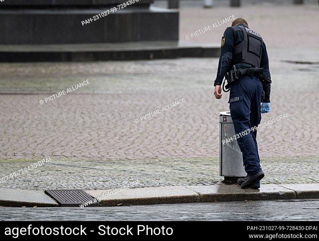 27 October 2023, Saxony, Dresden: A policeman checks a trash can on Theaterplatz. ""Lateral thinkers"" and right-wing extremists have registered demonstrations...